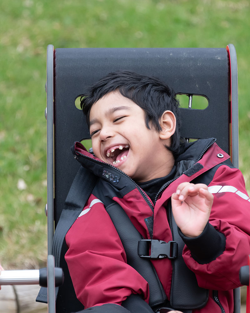 Close up of a child playing on a Springer, he is smiling uncontrollably in an inclusive Springer.